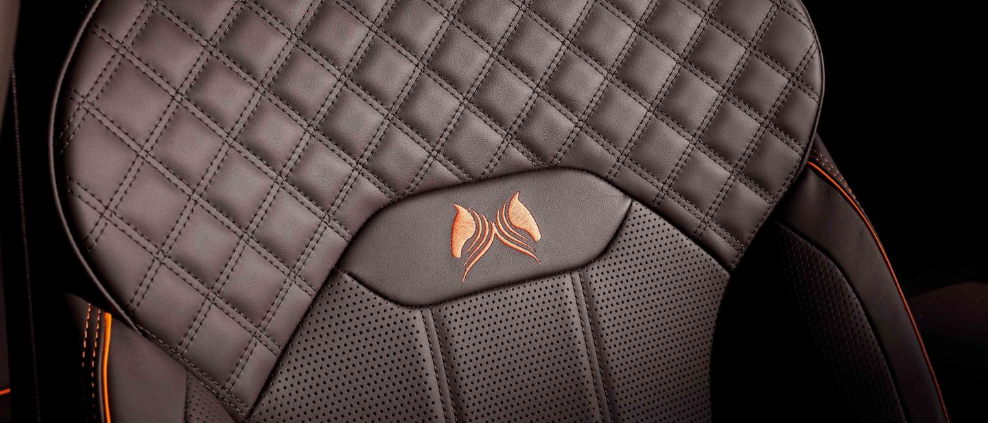 Bentley Bentayga Azure's front seat in focus, featuring detailed Diamond quilt detailed stitching and Orange flame piping witch custom emblem.